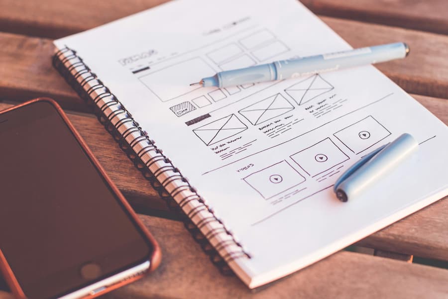 TSI: Notebook with UX design drawings beside an iPhone