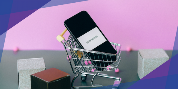 A mobile phone on top of a miniature grocery cart surrounded by boxes